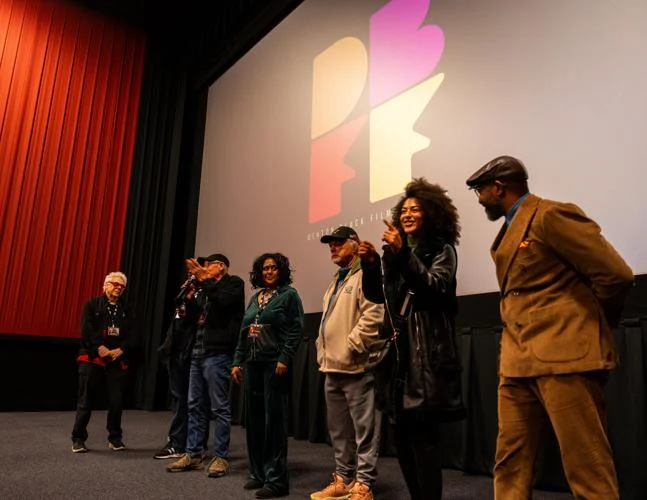 Filmmakers on stage in front of the Denton Black Film Festival screen before a theater audience